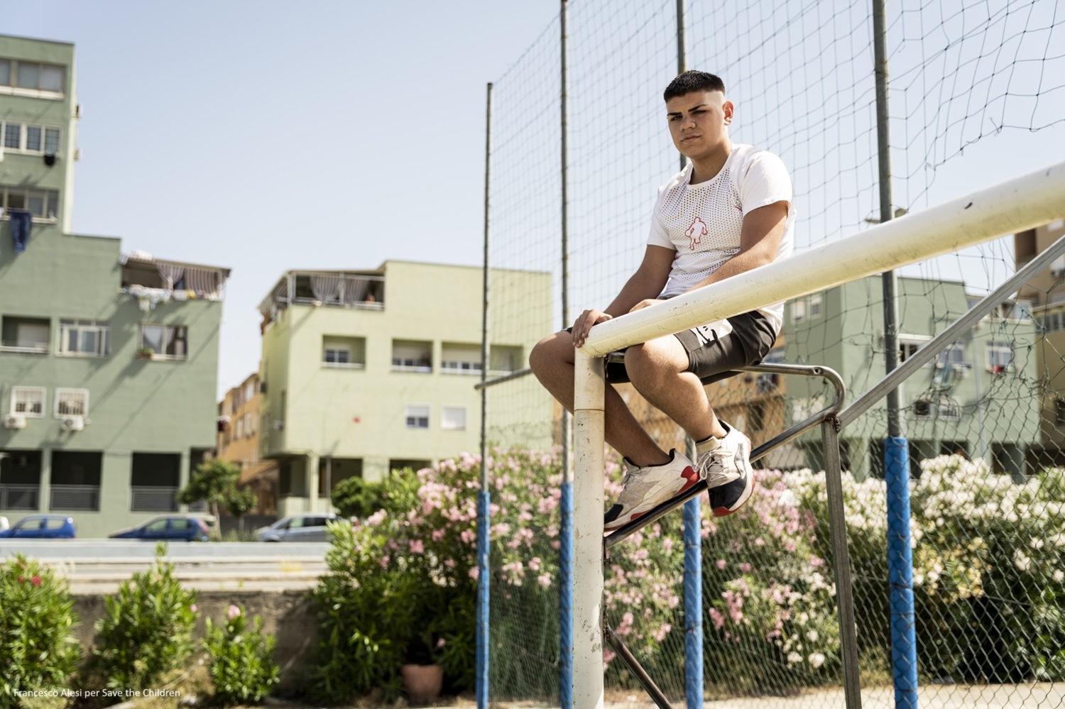 ragazzo seduto sopra porta da calcio in un campetto
