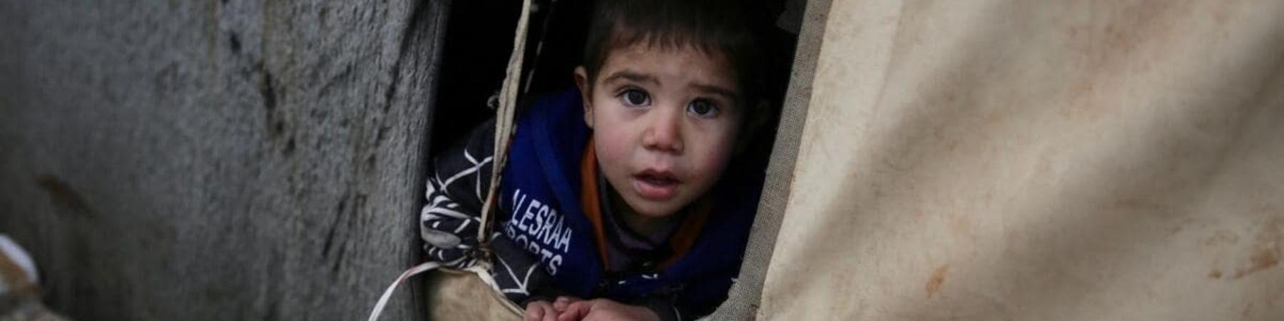 Karim bambino siriano che fuoriesce da tenda del campo profughi 