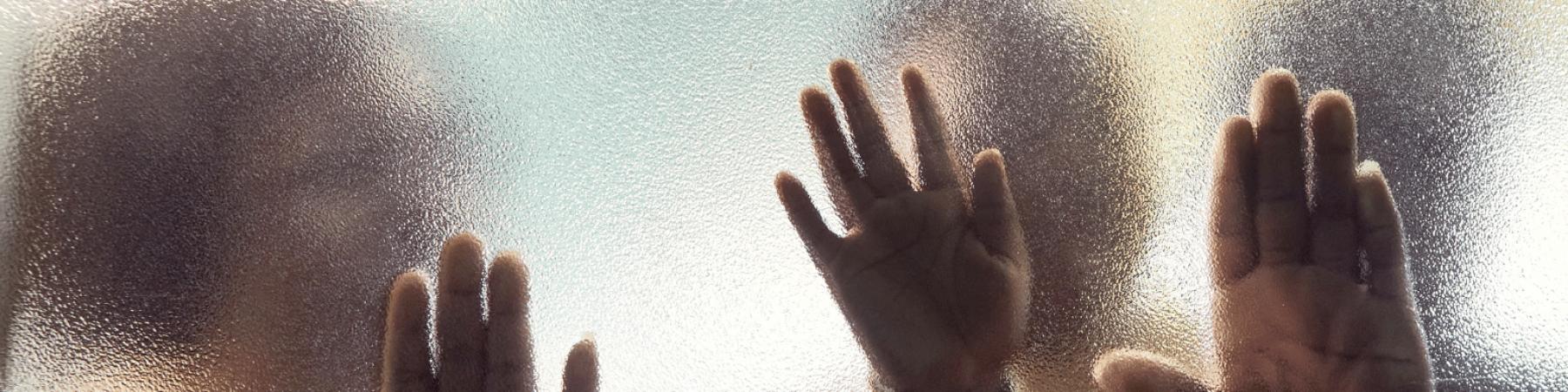 3 sagome di mani contro un vetro sfocato