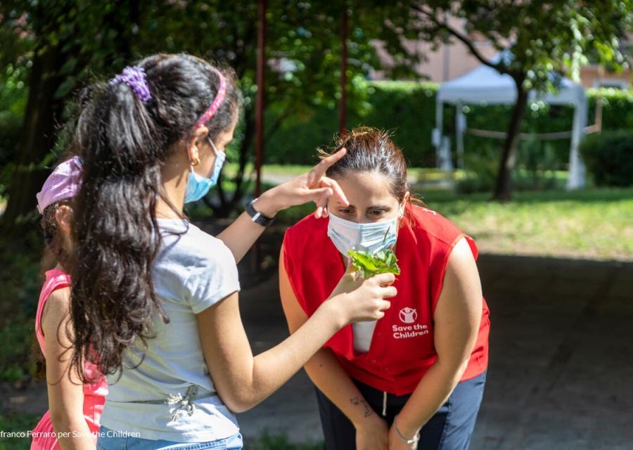 bambina che mostra una piantina all'operatrice save the children