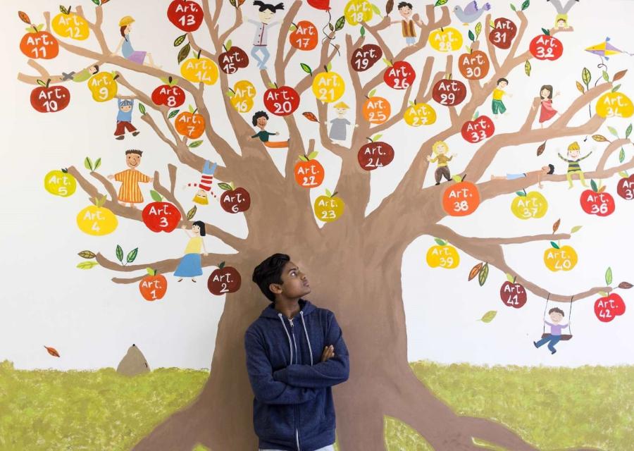 ragazzo davanti a un murales con un albero