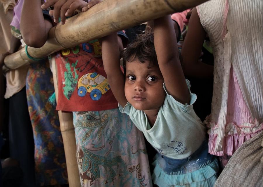 Bambina Rohingya mezzo busto guarda in camera. Immagine molto colorata.