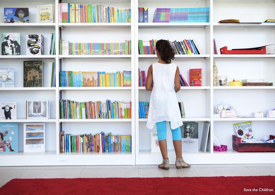 bambina in piedi davanti a una libreria all'interno di un punto luce