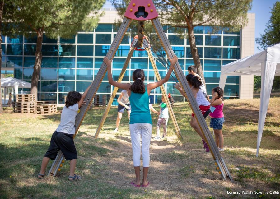 bambini che giocano intorno ad un'altalena nel parco del Punto Luce di Torre Maura