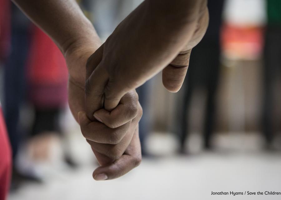 dettaglio su mani che si tengono, una di un bambino una di un adulto