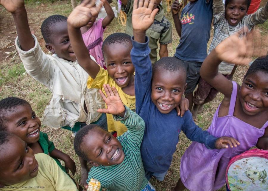 gruppo di bambini sorridenti con le mani alzate vestiti con diversi colori, foto dall'alto