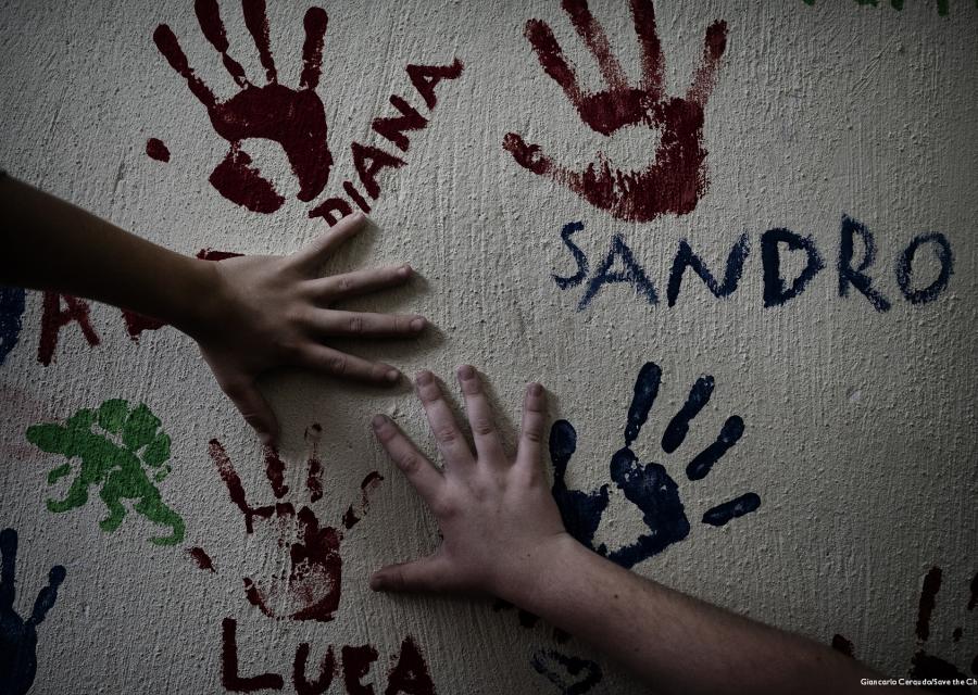 mani di bambini che appoggiate al muro disegnano la loro impronta colorata con la vernice