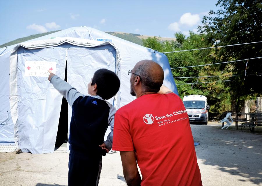 un operatore di save the children Italia con un bambino davanti a una tenda