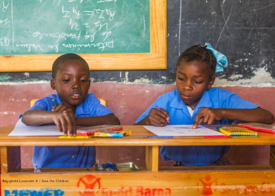 Due bambini di Haiti seduti ad un banco nella scuola costruita da Save the Children