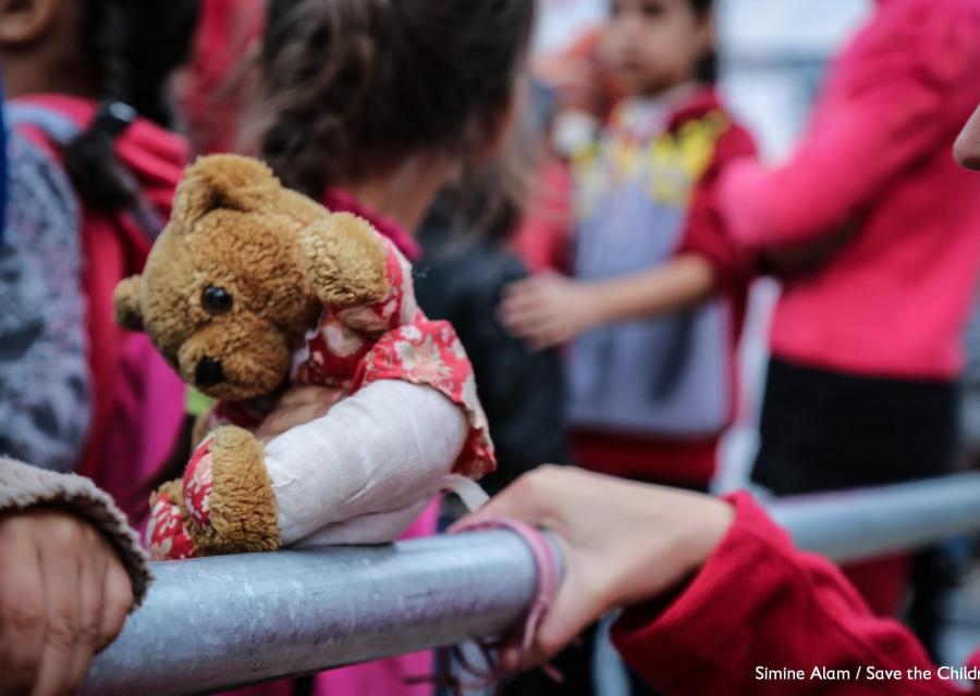 le mani di due bambini afferrano lastra di acciaio accanto a peluche in primo piano