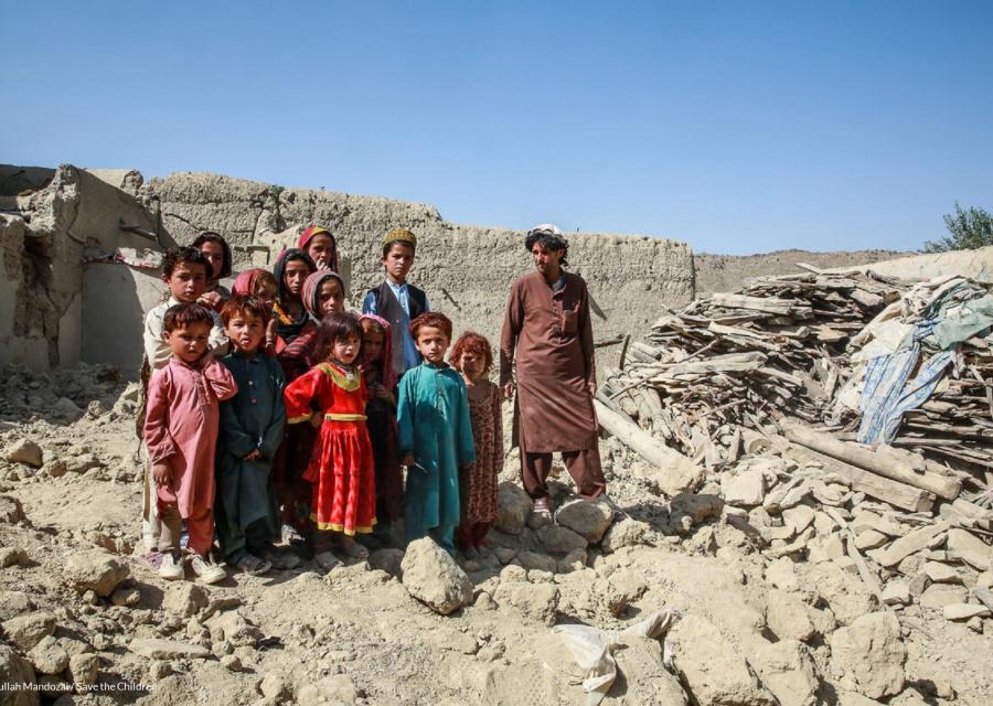 Bambine e bambini con accanto uno zio in mezzo ai detriti della loro casa distrutta dal terremoto in Afghanistan