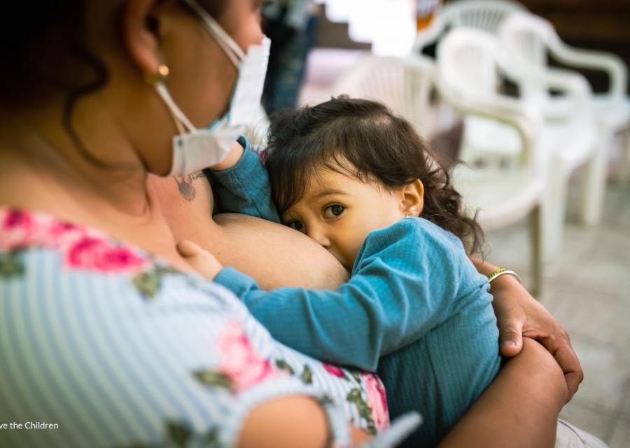 Una mamma ripresa lateralmente mentre allatta il proprio bambino