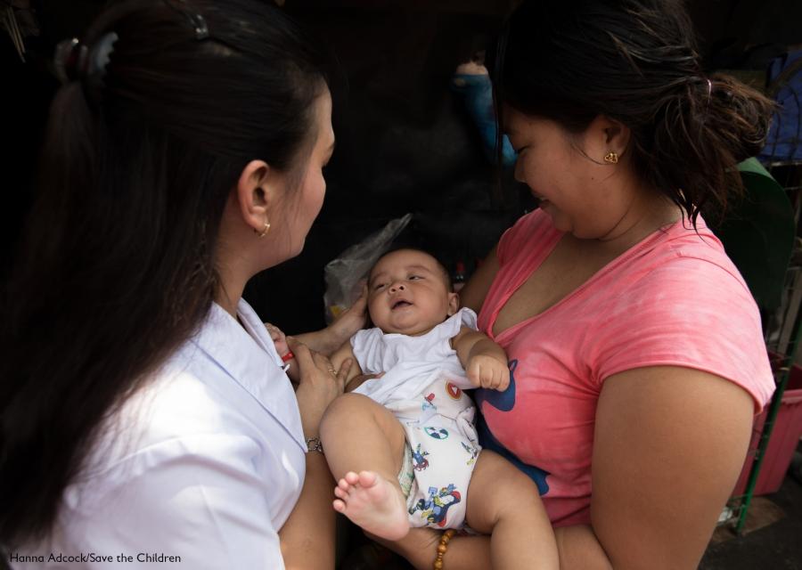 mamma con in braccio la sua bimba neonata insieme a un operatrice di Save the Children