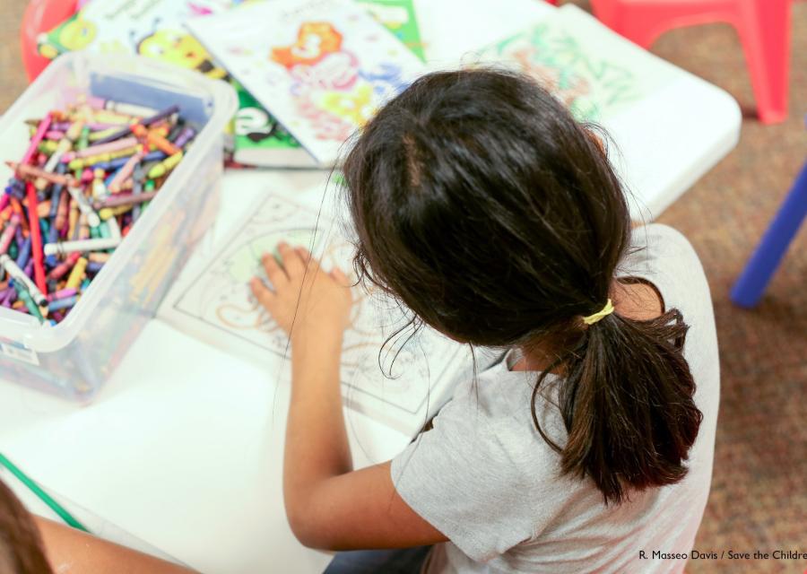 bambina ad un tavolo che colora e disegna