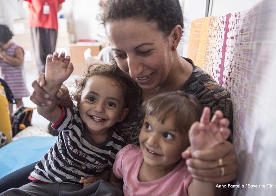 Una mamma abbraccia e guarda due bambini piccoli sorridenti