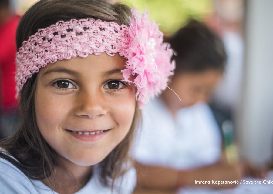 Primo piano bambina sorridente con fascia rosa in testa