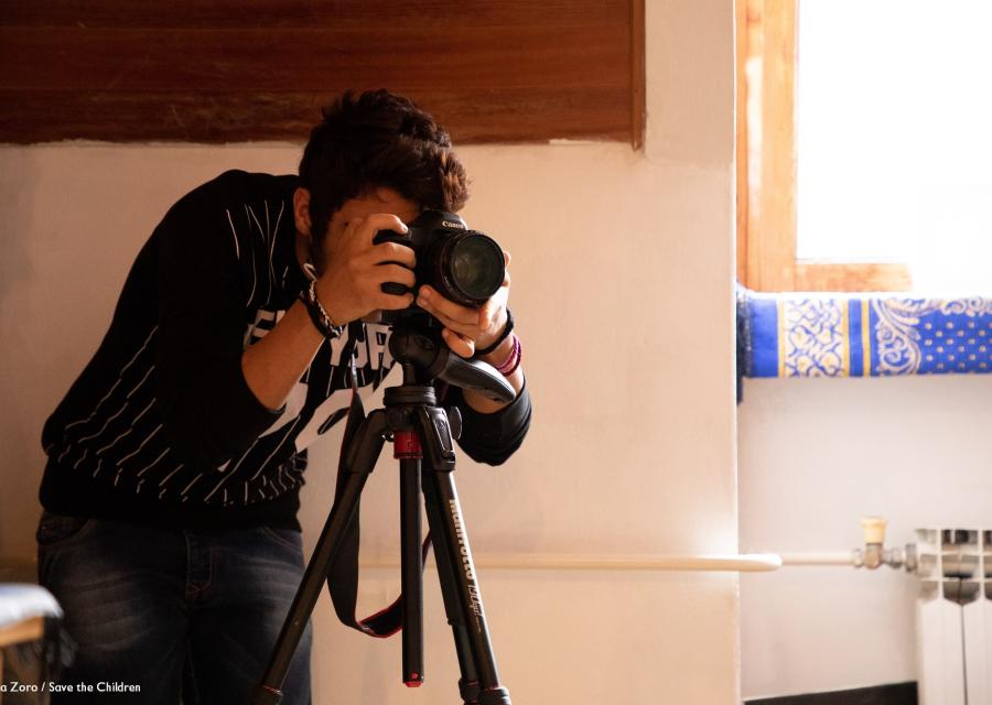 operatore video chinato sulla sua videocamera mentre fa delle riprese in una stanza