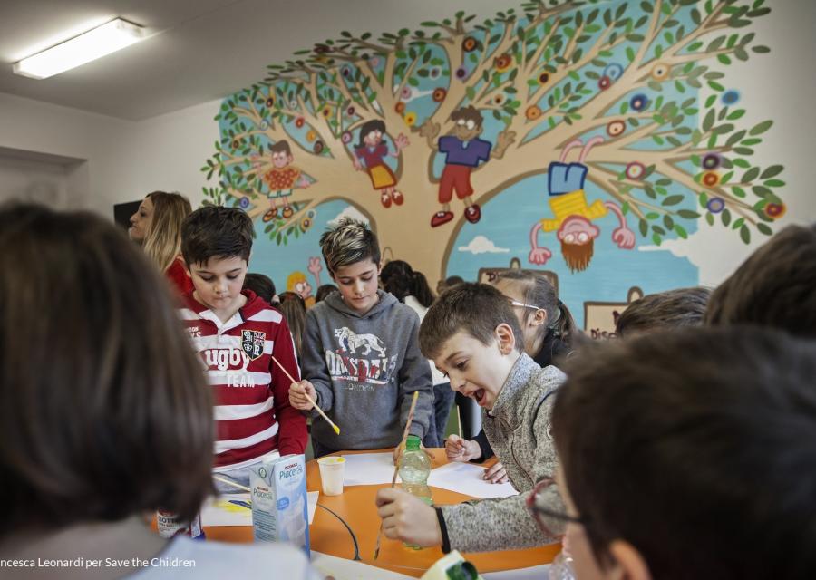 bambini a un tavolo a scuola mentre disegnano insieme con dei pennelli