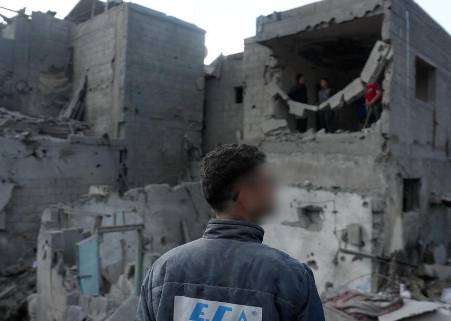 uomo di spalle di fronte ad un palazzo distrutto a Gaza