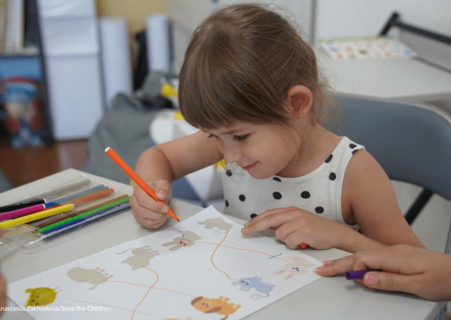 bambina seduta a un tavolo mentre fa i compiti con metodo creativo 