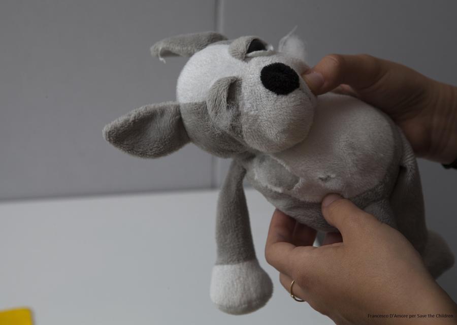 mani tengono un peluche rovinato a forma di cane 