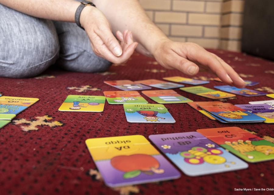 primo piano di card colorate appoggiate a terra e mani di un adulto che le tocca