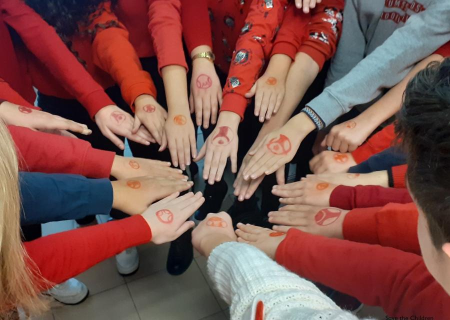 mani di ragazzi che si uniscono e sulle loro mani il logo di save the children