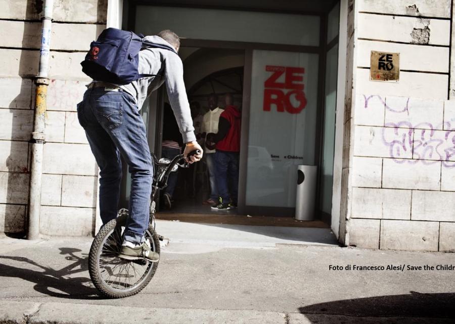 Ragazzo di spalle su monociclo davanti a entrata del centro civicozero roma