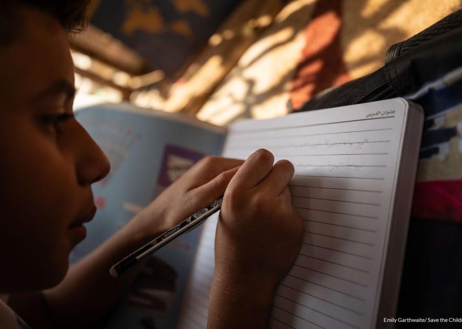 prio piano di un bambino mentre scrive su un quaderno
