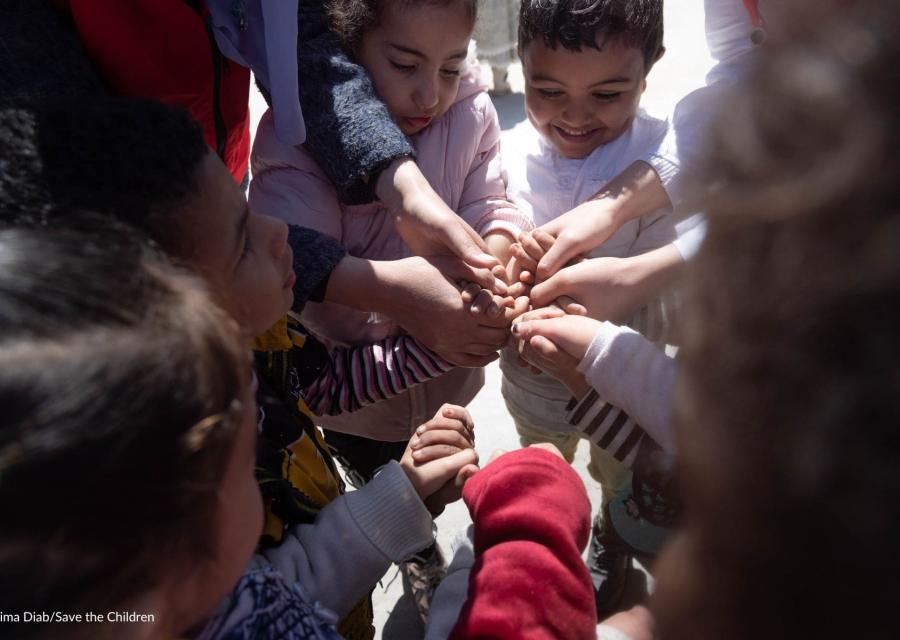 bambini in cerchio che ridono e si stringono le mani 