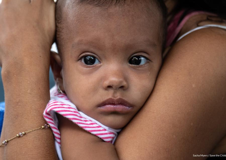 il viso di un bambino è stretto tra le braccia della mamma