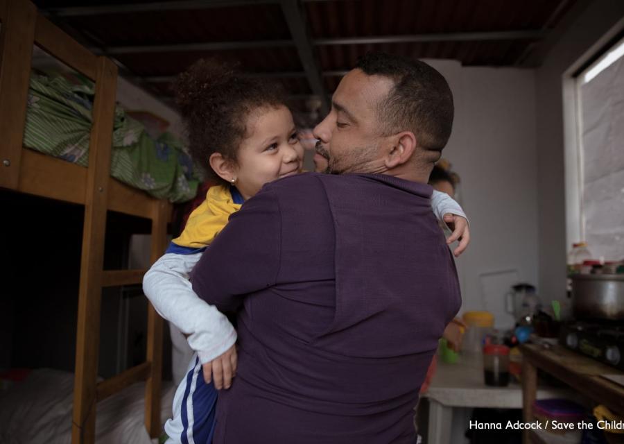 Un papà tiene in braccio e sorride a sua figlia
