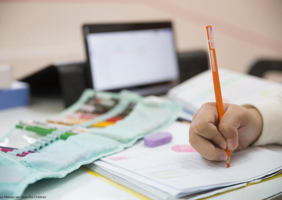 Primo piano di un quaderno su cui un bambino sta scrivendo con una matita