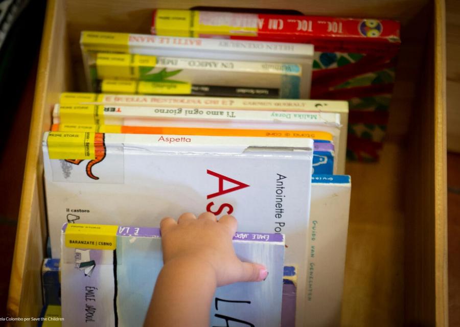 mano di un bambino che sceglie da una scatola di libri