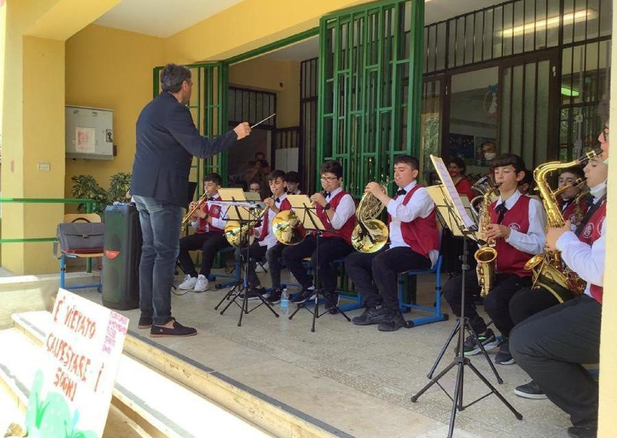 Insegnante che dirige l'orchestra di studenti che suonano strumenti musicali come trombe e flauti 
