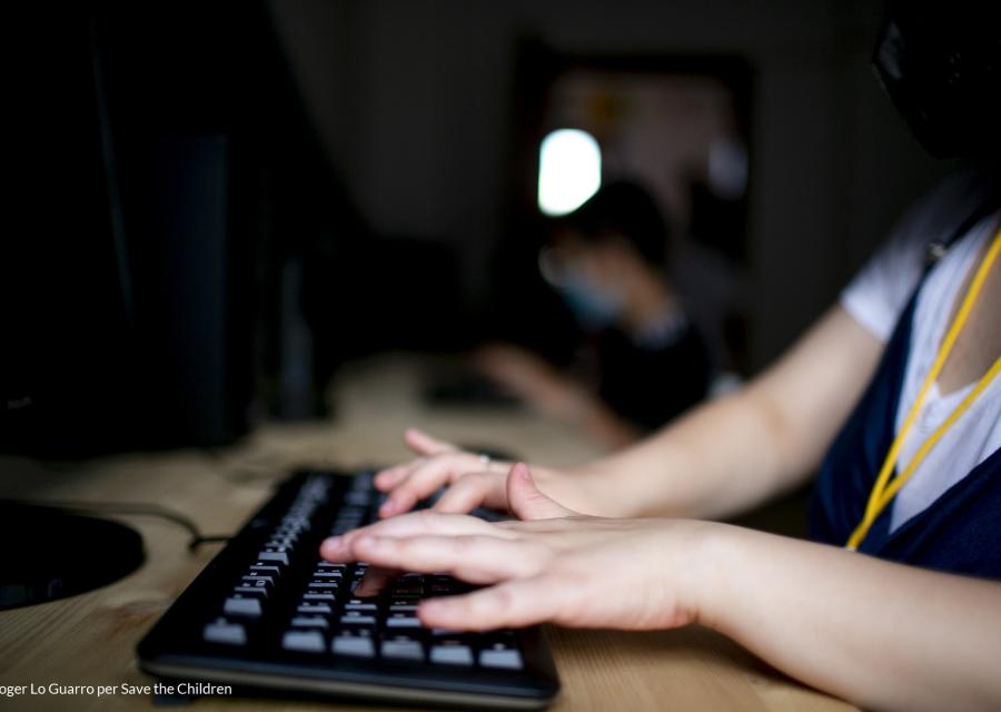 dettaglio delle mani di una bambina o bambino che scrive su una tastiera del PC