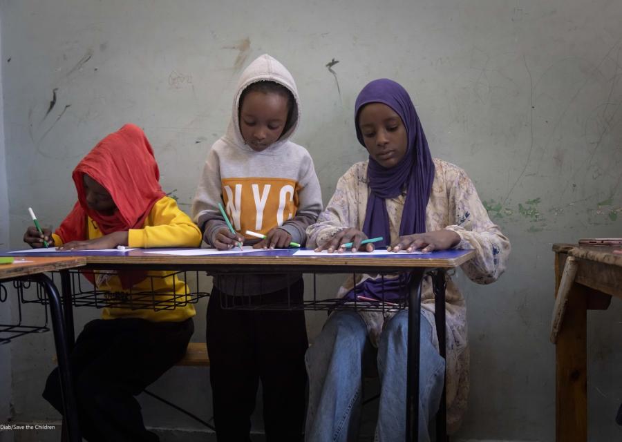 Tre bambine sedute ad un banco di scuola
