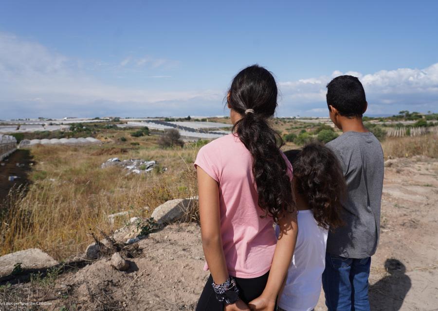 tre bambini di spalle di fronte una serra agricola nella fascia trasformata di ragusa 