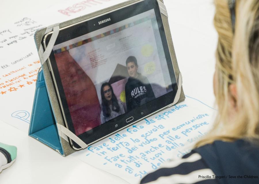 bambina bionda di spalle davanti a uno schermo di un tablet 
