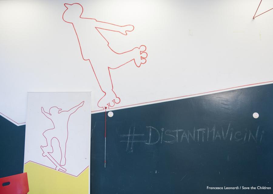 Muro interno di un Punto Luce di Save the Children con la scritta #DistantimaVicini