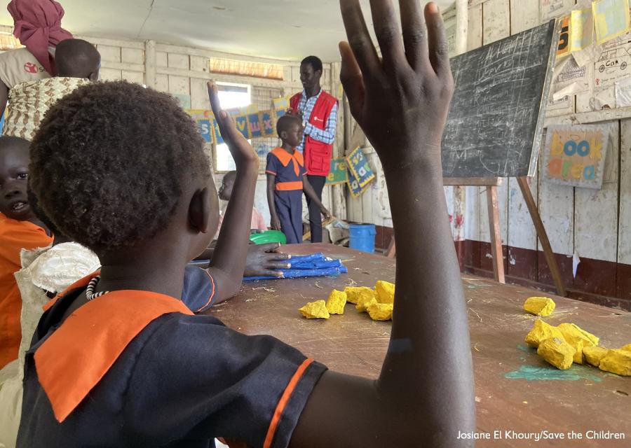 bambina ugandese di spalle con mano alzata durante lezione in classe