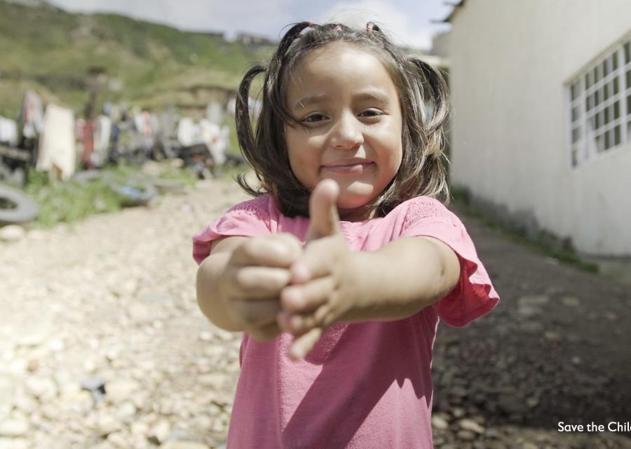 Una bambina messicana con codini e maglietta rosa mostra come ha imparato a lavarsi le mani.