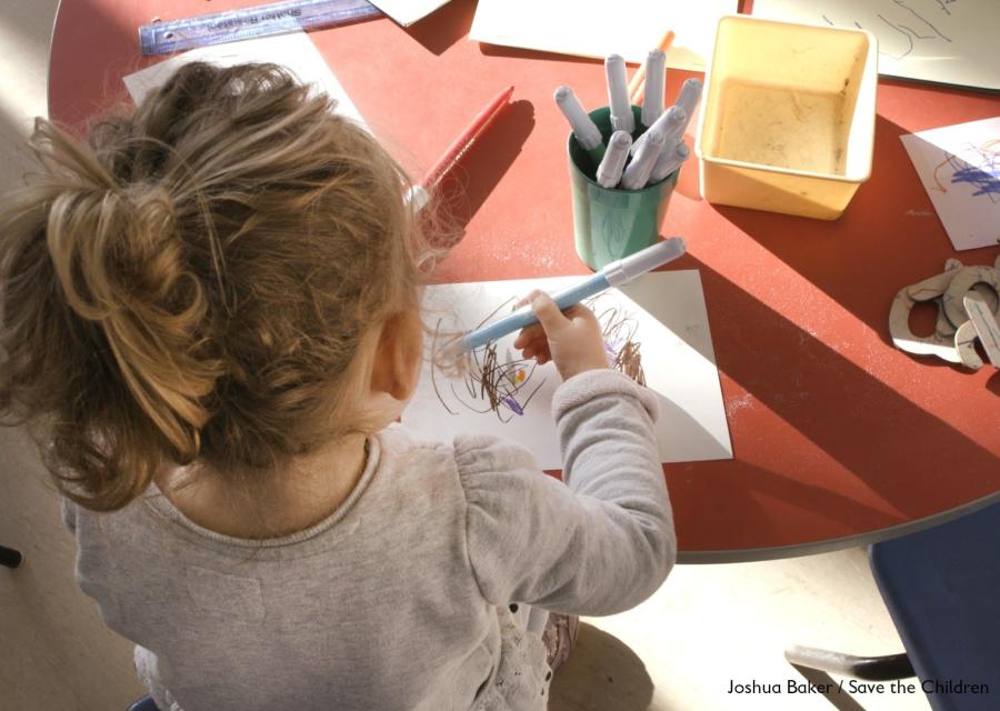 bambina di spalle alla scrivania che colora e disegna