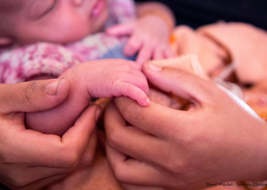 dettaglio delle mani di una mamma che tengono la mano del suo neonato