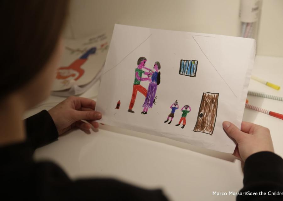 Bambina di spalle tiene in mano un disegno che rappresenta una scena di violenza domestica e assistita