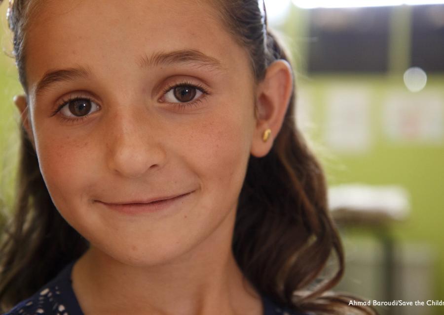 Primo piano di una bambina bionda sorridente che guarda in camera