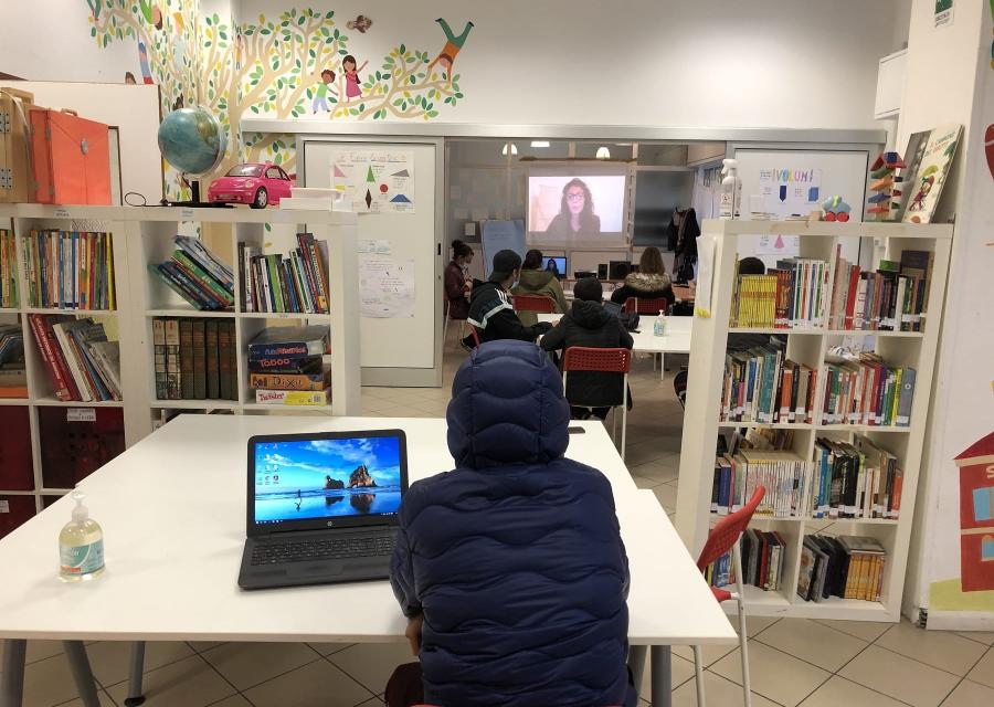 Bambino seduto di spalle con computer accesso al lato