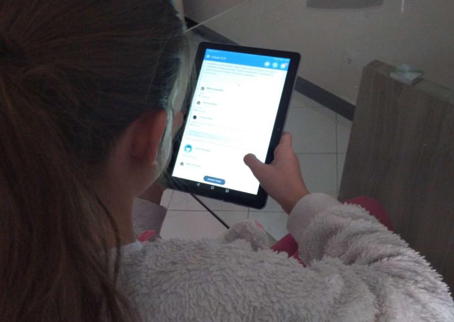 Bambina di spalle tiene un tablet accesso in mano