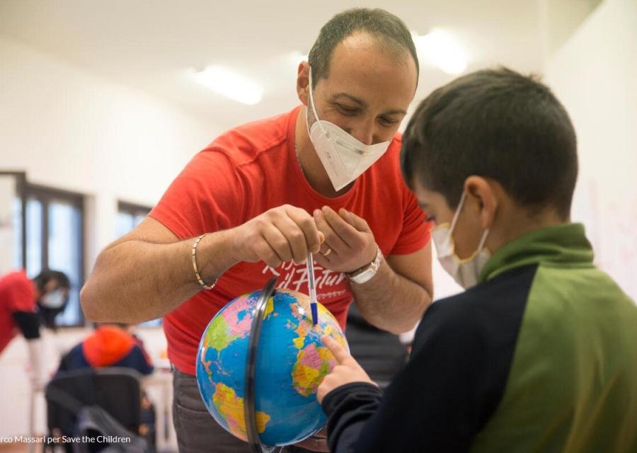 Educatore sava the children che mostra un mappamondo ad un bambino 