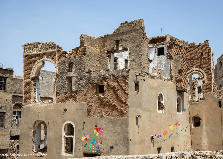 case e palazzine in macerie a causa dei bombardamenti, su queste alcuni fiori disegnati in segno di pace